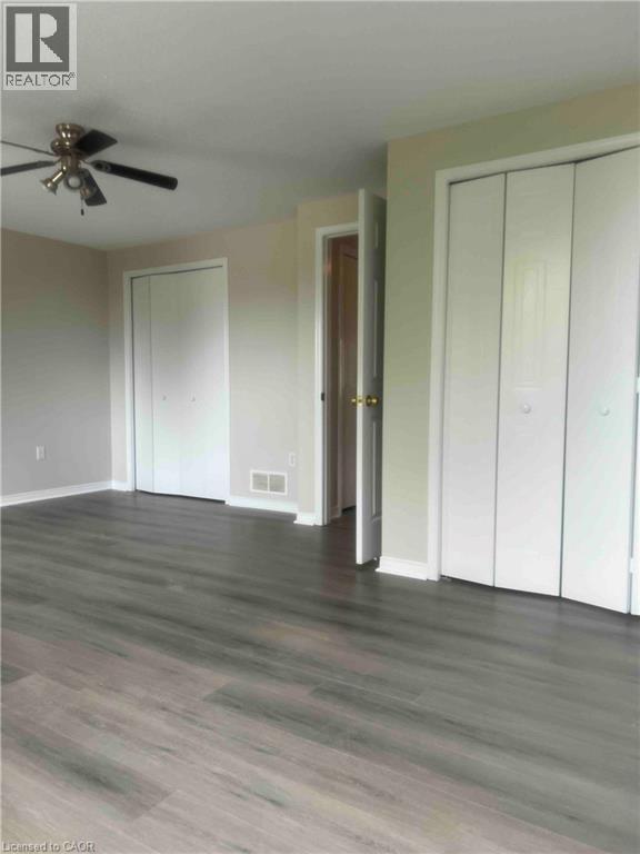 Spacious interior room featuring wood-finish flooring, light-toned walls, and a ceiling fan - 151 Clairfields Drive E Unit# 4, Guelph, ON