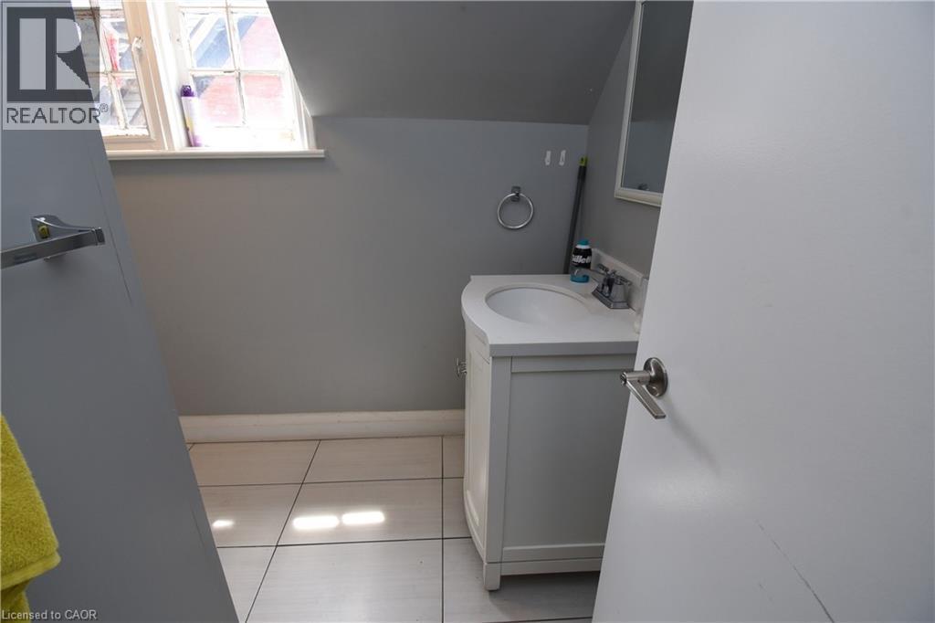 Bathroom featuring a white vanity with an integrated sink, polished chrome faucet, and a rectangular mirror - 242 James Street S, Hamilton, ON