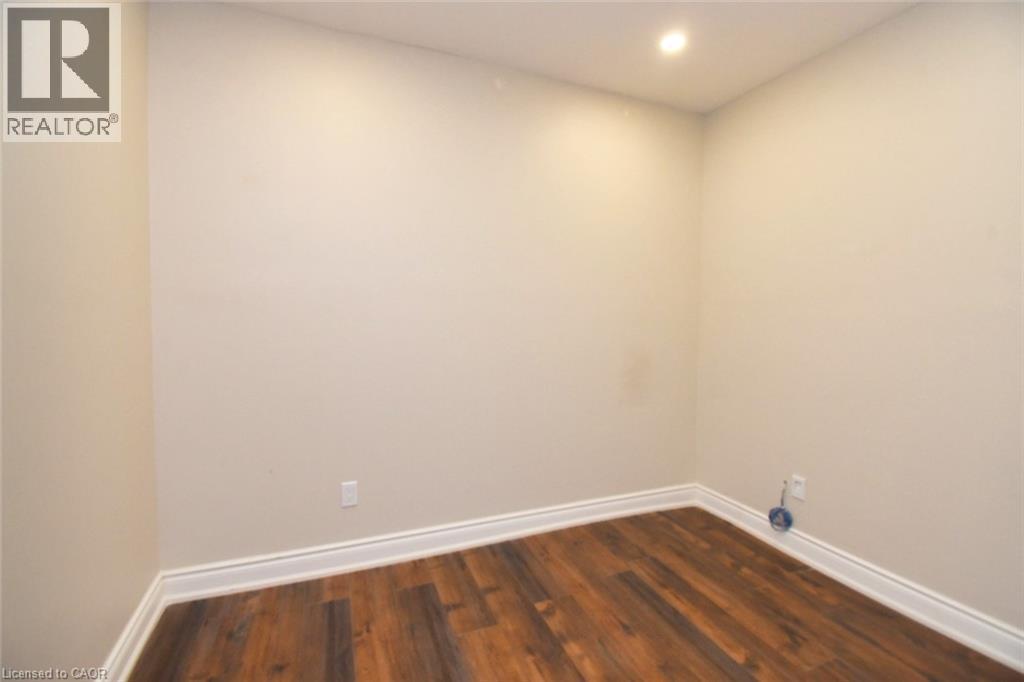 Recessed ceiling light illuminating a room with wood-finish flooring and white baseboards - 242 James Street S, Hamilton, ON