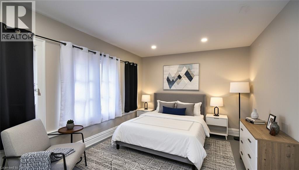 Spacious room featuring recessed lighting, a wide window with sills, neutral wall tones, and wood-finish flooring with an area rug - 242 James Street S, Hamilton, ON