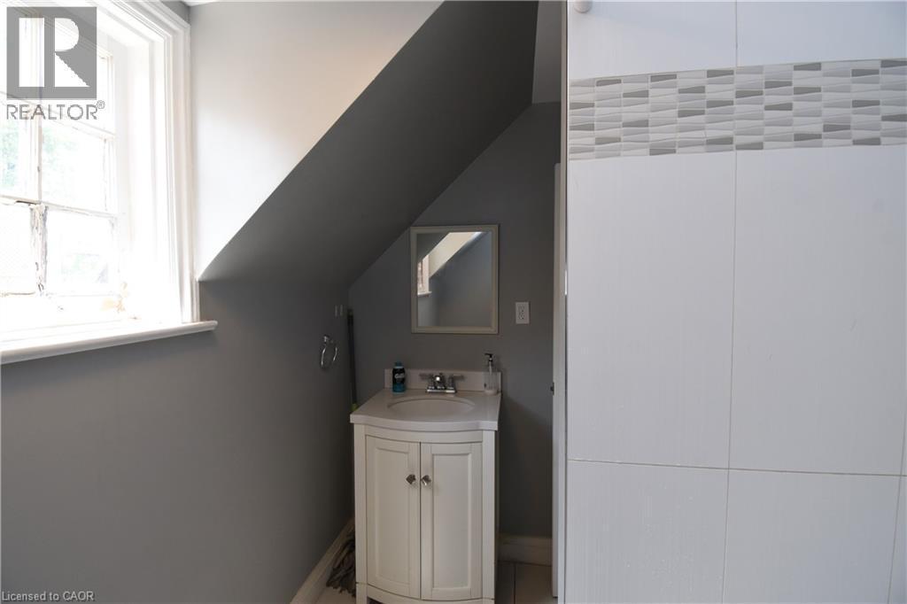 Compact bathroom featuring a white vanity with a basin sink and a framed mirror - 242 James Street S, Hamilton, ON