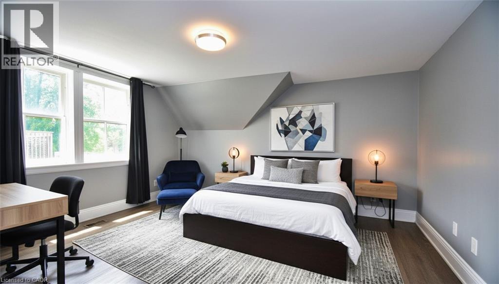 Bedroom featuring wood-finish flooring, overhead lighting, and multiple windows - 242 James Street S, Hamilton, ON