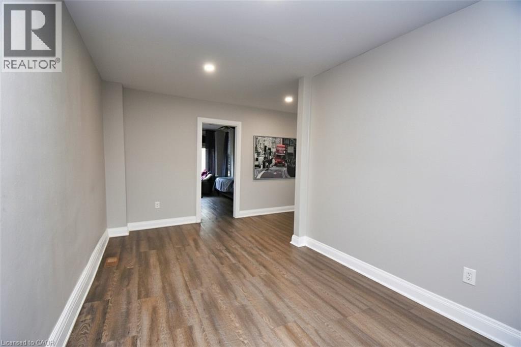 Interior corridor featuring wood-finish flooring, light gray wall paint, recessed lighting, and white baseboards - 242 James Street S, Hamilton, ON