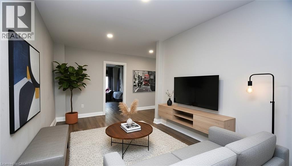 Living area featuring light gray walls, recessed lighting, wood-finish flooring, and a floating media console - 242 James Street S, Hamilton, ON