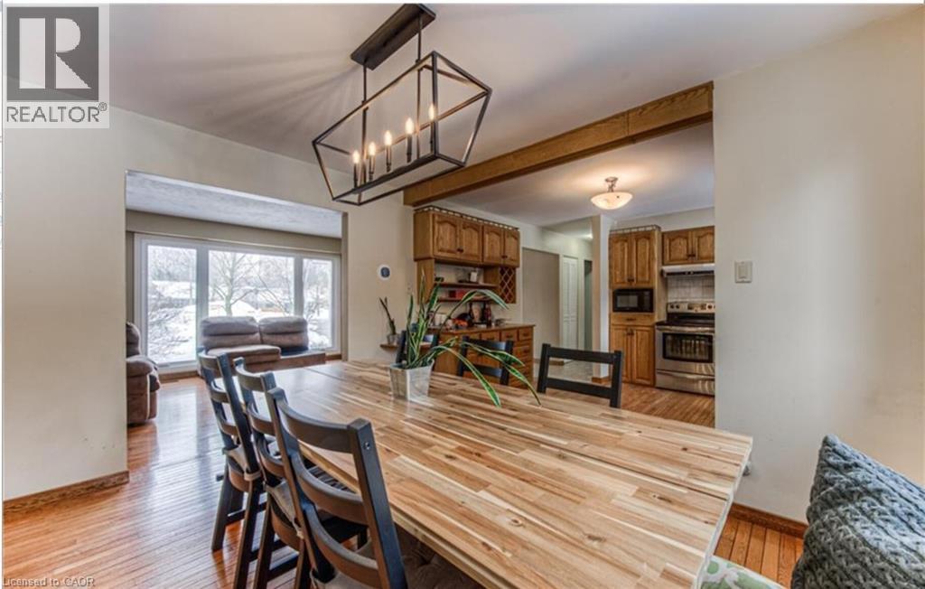 Dining area featuring wood-finish flooring, a contemporary linear chandelier, and a wood beam accent - 110 Wren Place Unit# Upper, Kitchener, ON - Indoor Photo Showing Dining Room