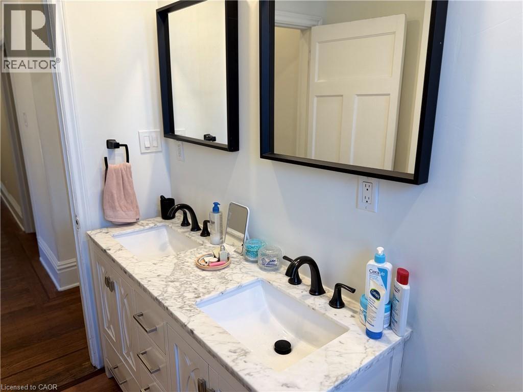 Dual basin vanity featuring a marble-patterned countertop, under-mount sinks, and matte black fixtures - 207 Charlton Avenue W, Hamilton, ON