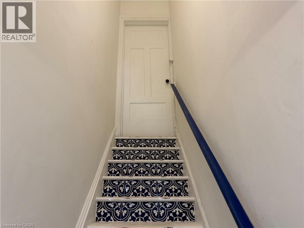 Staircase with contrasting patterned risers and a dark blue handrail - 207 Charlton Avenue W, Hamilton, ON