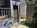 Exterior entrance with dark brown paneled door, gray wood siding, and an overhead light fixture - 207 Charlton Avenue W, Hamilton, ON 