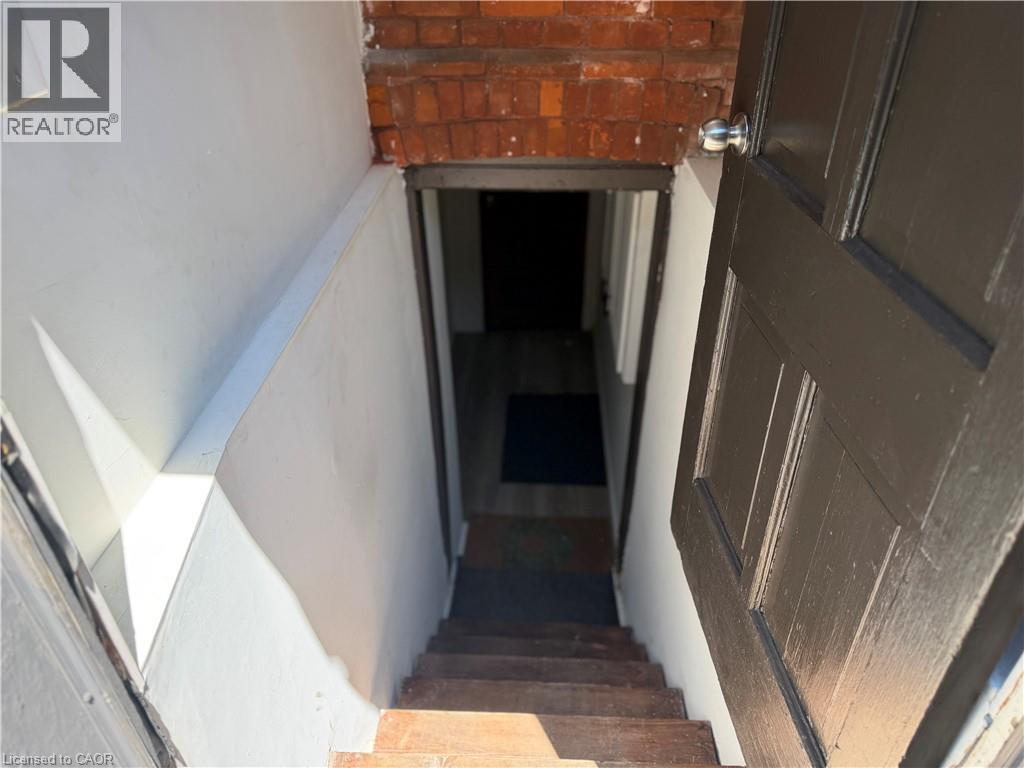 Staircase with wood treads and a dark wood door featuring a chrome doorknob - 207 Charlton Avenue W, Hamilton, ON