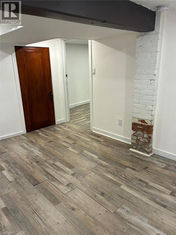 Wood-finish flooring, exposed brick structural column, dark-stained wood door, and structural wood beam - 207 Charlton Avenue W, Hamilton, ON