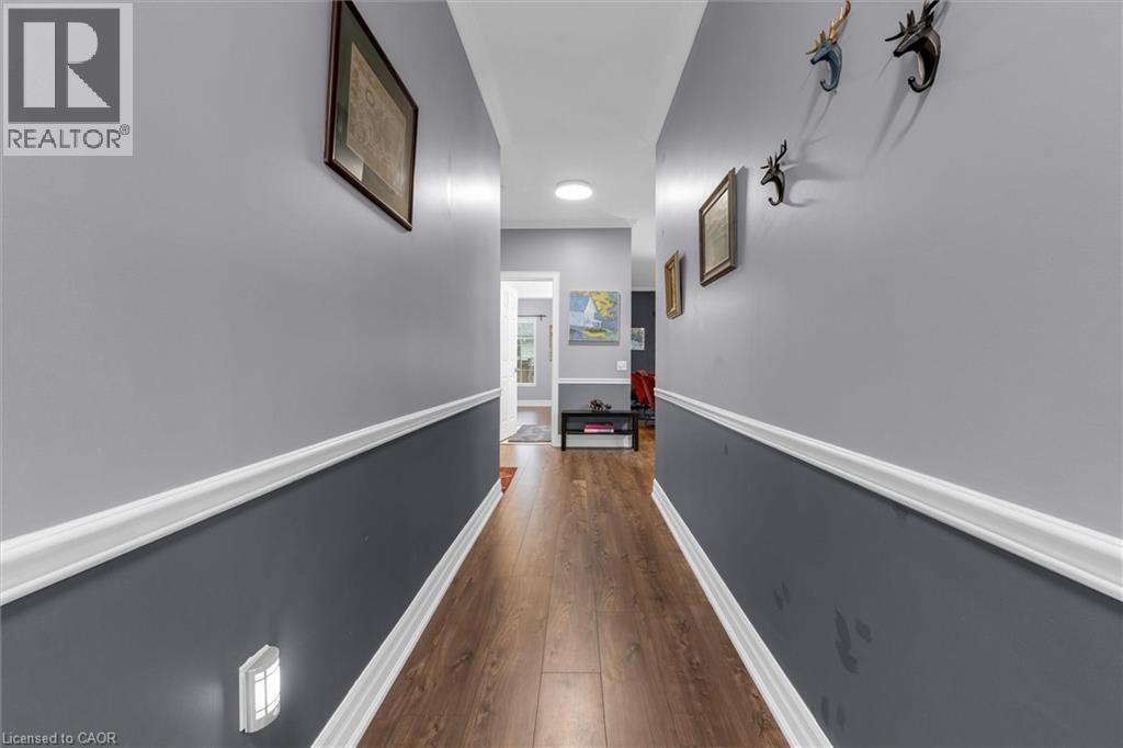 Hallway featuring wood-finish flooring, two-tone wall paint, white chair rail molding, and a flush-mount ceiling light - 149 Silverbirch Boulevard, Hamilton, ON