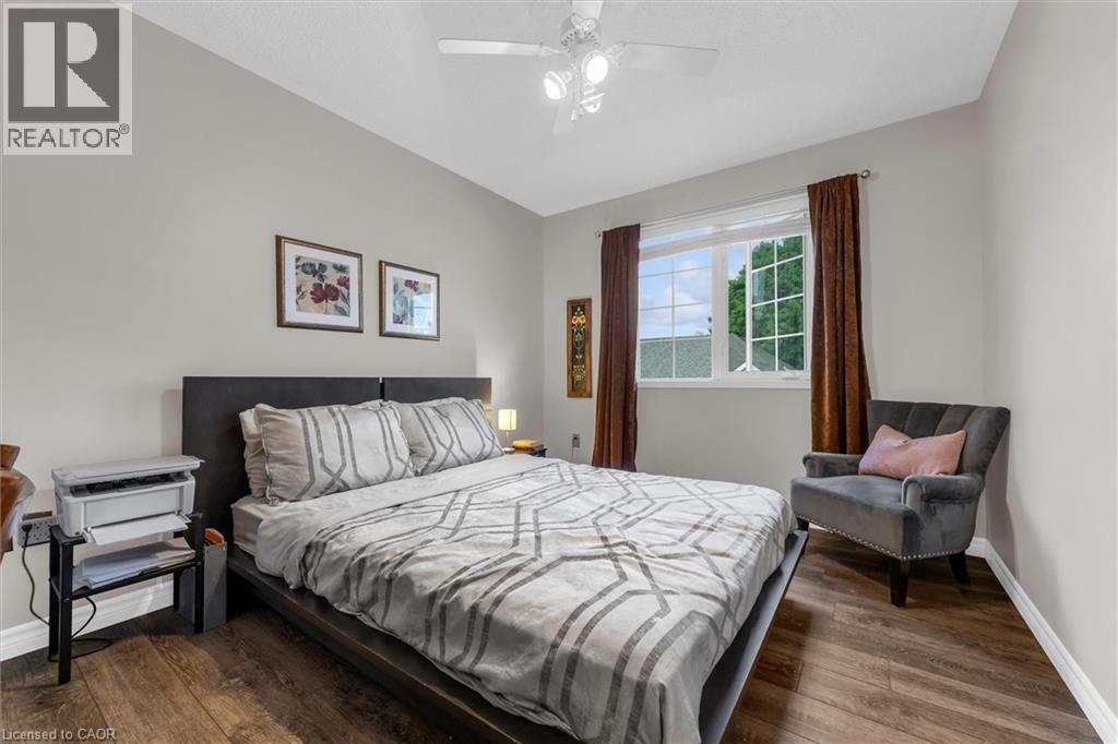 Bedroom featuring wood-finish flooring, a contemporary window with white framing, and a ceiling fan with integrated lighting - 149 Silverbirch Boulevard, Hamilton, ON