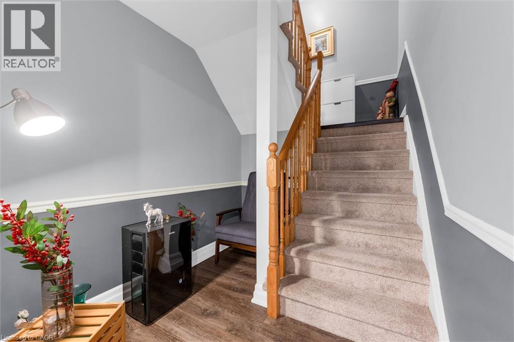 Staircase with carpeted treads and natural wood railing, complemented by two-tone painted walls with chair rail molding - 149 Silverbirch Boulevard, Hamilton, ON