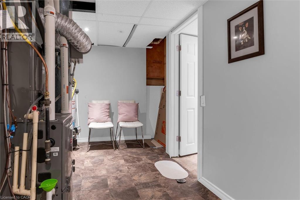 Utility area with durable flooring, neutral wall tones, white trim, and a paneled interior door - 149 Silverbirch Boulevard, Hamilton, ON