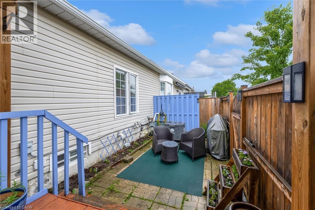 Patio area featuring brick paving, wood fencing, and exterior wall lighting - 149 Silverbirch Boulevard, Hamilton, ON
