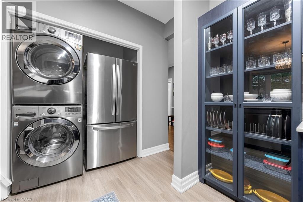 Stainless steel stacked washer and dryer appliances alongside a stainless steel refrigerator - 149 Silverbirch Boulevard, Hamilton, ON