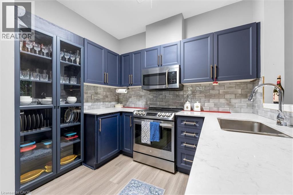Modern kitchen featuring blue shaker-style cabinetry and light wood-finish flooring - 149 Silverbirch Boulevard, Hamilton, ON