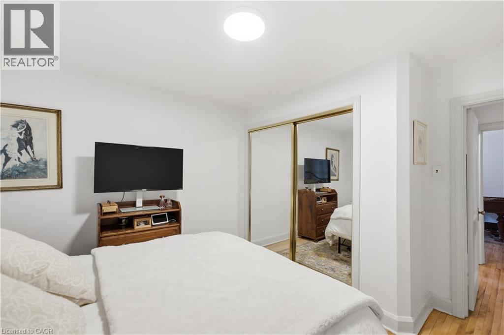 White-painted room featuring a built-in closet with mirrored sliding doors, recessed ceiling lighting, and wood-finish flooring visible through the doorway - 81 Vale Avenue, St. Catharines, ON