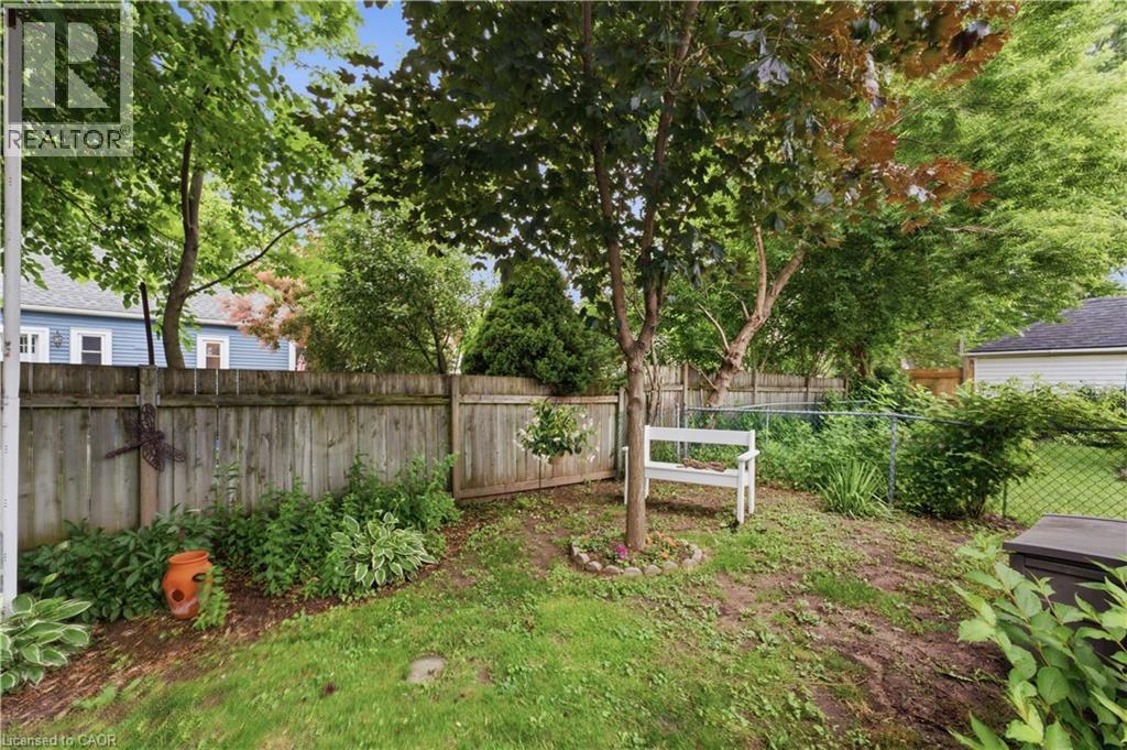 Fenced backyard featuring mature trees, a lawn area, and established plantings - 81 Vale Avenue, St. Catharines, ON