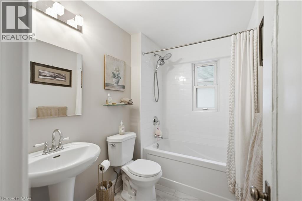 Bathroom featuring a pedestal sink, a toilet, and a bathtub with white subway tile surround - 81 Vale Avenue, St. Catharines, ON