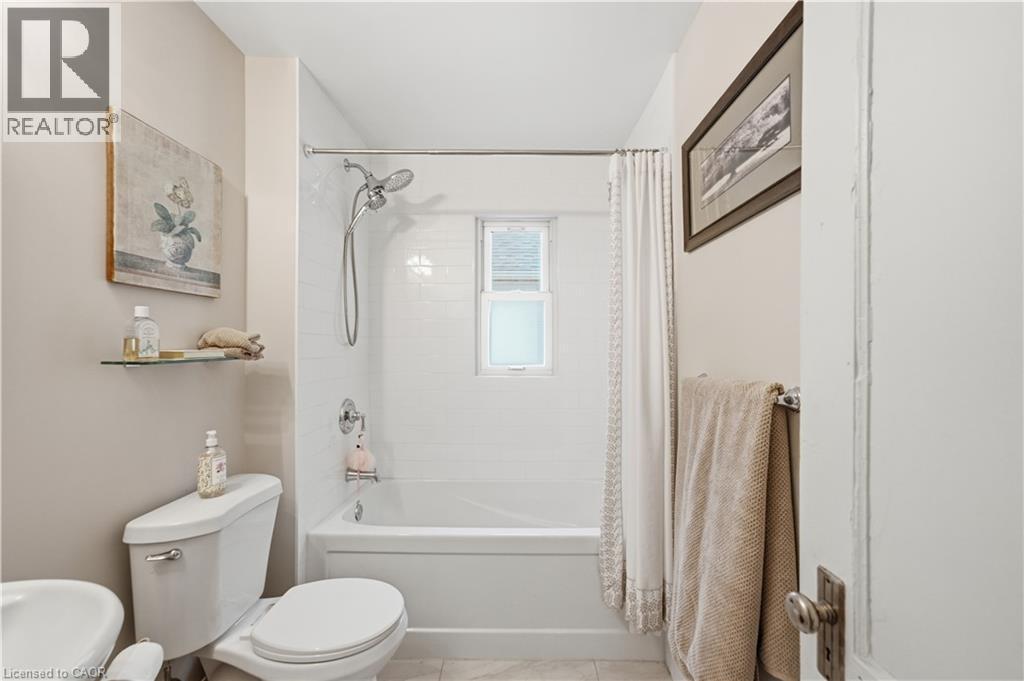 Bathroom featuring a white subway tile shower surround with a built-in window, a chrome showerhead, and a matching tub - 81 Vale Avenue, St. Catharines, ON