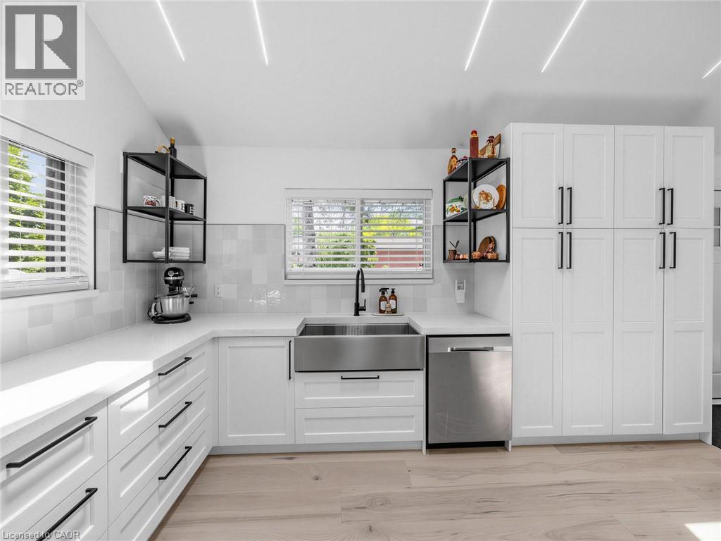 Modern kitchen featuring white shaker cabinetry with black hardware, an undermount stainless steel farmhouse sink, and light wood-finish flooring - 13 Swanhurst Boulevard, Mississauga, ON - Indoor Photo Showing Kitchen