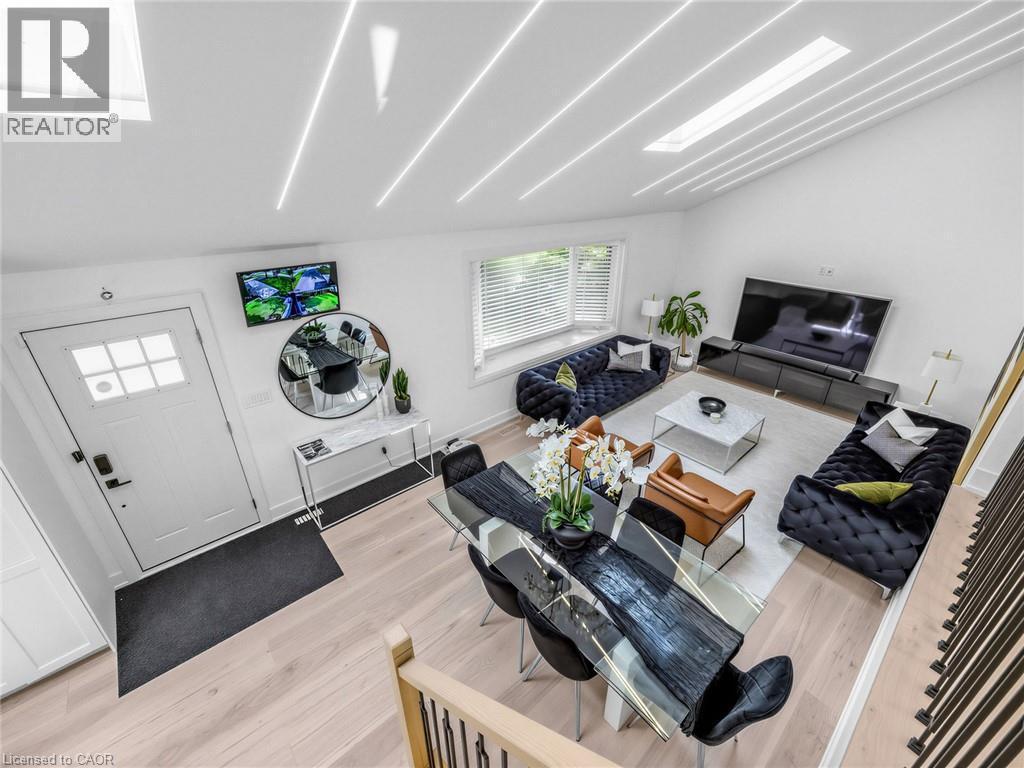 Open-concept living and dining area featuring light wood-finish flooring, a vaulted ceiling with integrated linear lighting, and a large skylight - 13 Swanhurst Boulevard, Mississauga, ON - Indoor