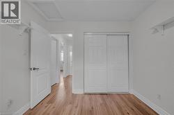 Interior room featuring wood-finish flooring, white walls, and a white sliding closet door -
