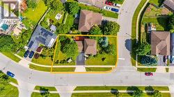 Aerial perspective showcasing a corner lot property with mature trees, a driveway, and surrounding streets -