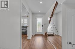 Entryway featuring wood-finish flooring, recessed lighting, and a white paneled door -