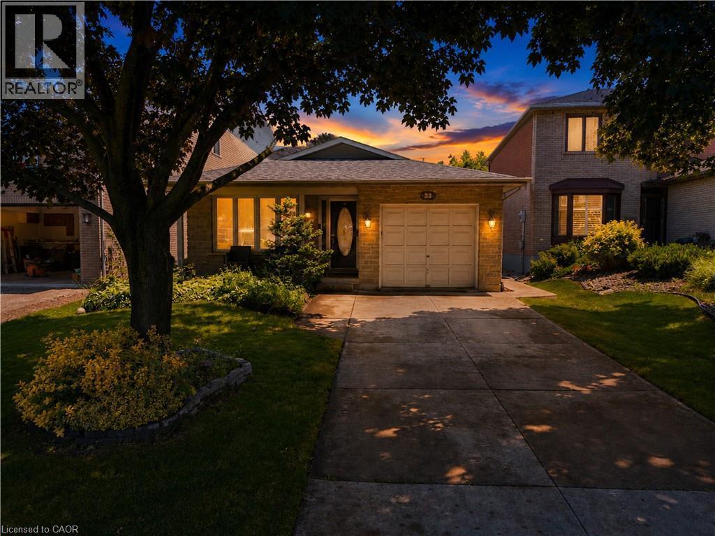 Brick facade residence featuring an attached garage with carriage-style door, a paved driveway, and established front yard landscaping - 23 Millpond Place, Mountain, ON