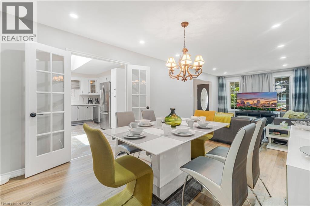Dining area featuring wood-finish flooring, a contemporary dining table, and a bronze chandelier - 23 Millpond Place, Mountain, ON