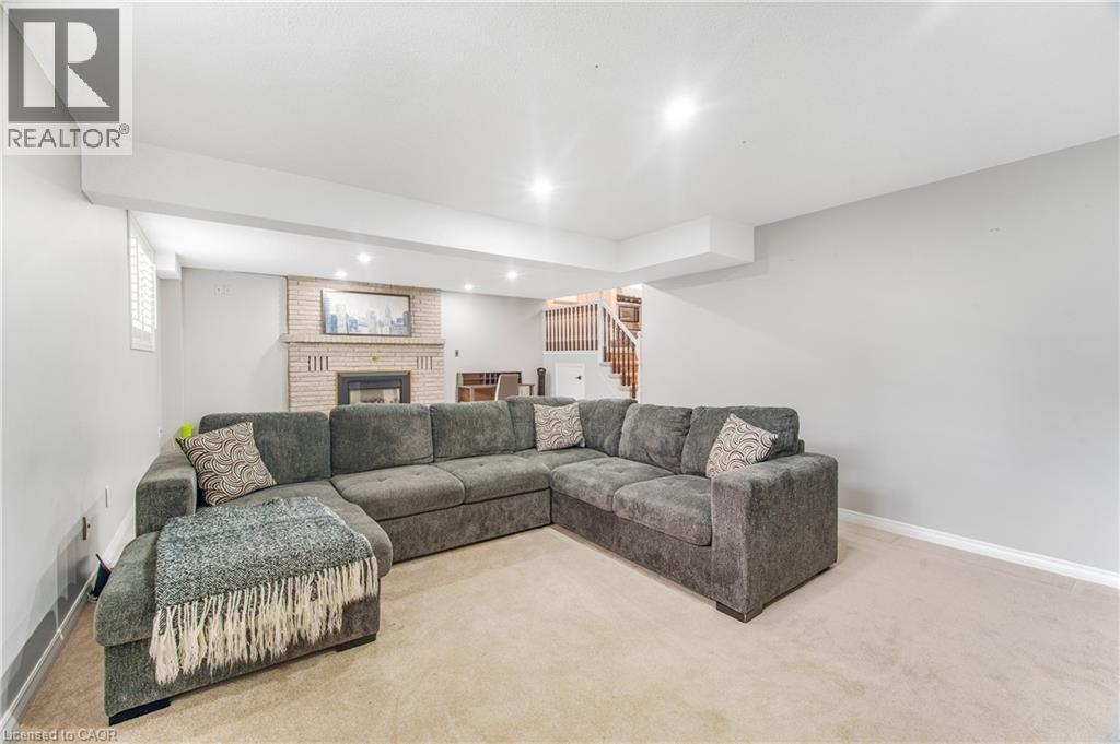 Carpeted recreation room featuring a brick fireplace with a mantel, recessed lighting, and a window with white louvered blinds - 23 Millpond Place, Mountain, ON