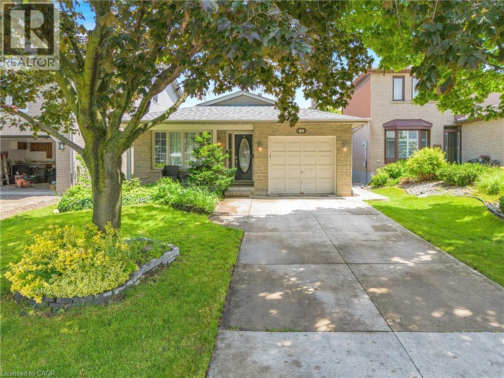 Stone veneer facade featuring a two-car garage, concrete driveway, and mature landscaping - 23 Millpond Place, Mountain, ON