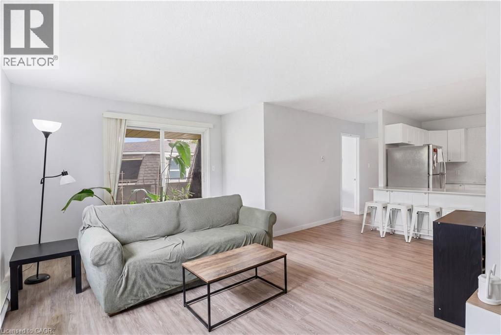 Open-concept living area featuring wood-finish flooring, white walls, and a sliding glass door - 91 Westmount Road Unit# 3, Waterloo, ON