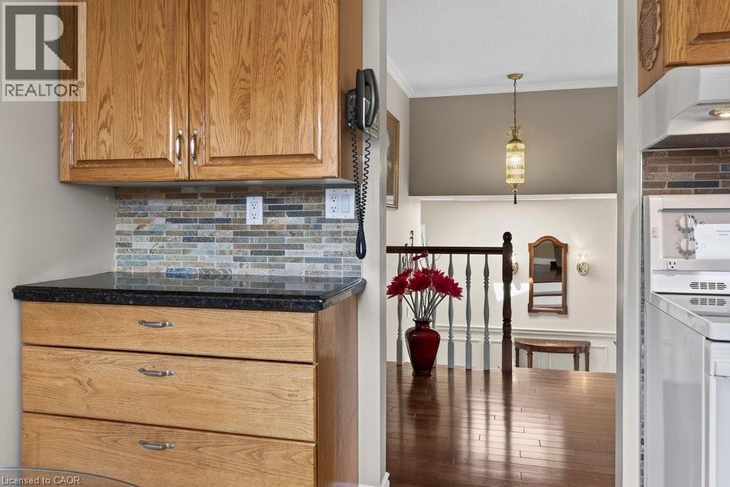 Kitchen cabinetry with a dark countertop and multicolor tile backsplash - 409 Mohawk Road W, Hamilton, ON