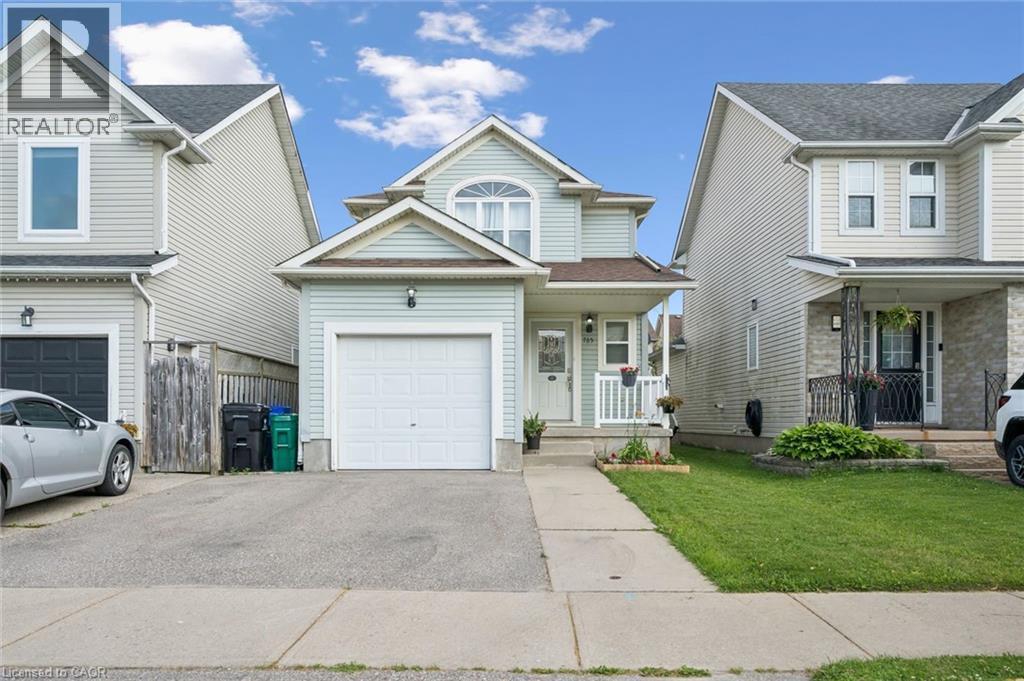 Two-story residence featuring light blue siding, a white garage door, and a covered porch with white railings - 765 Angler Way, Waterloo, ON
