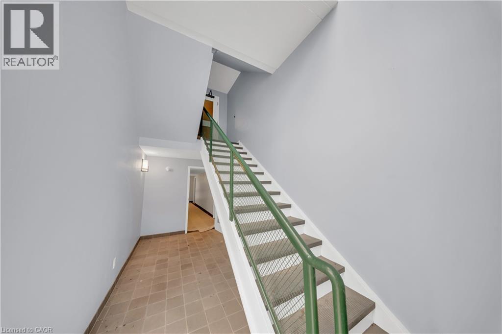 Stairwell featuring a green metal handrail with cable infill, white risers, and neutral-toned treads - 3085 Kingsway Drive Unit# 21, Kitchener, ON