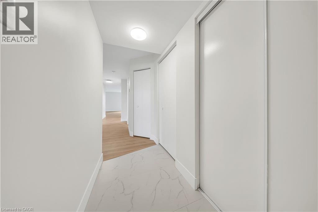 Hallway featuring white walls, recessed ceiling lighting, a white ceiling, light wood-finish flooring, and white sliding closet doors - 3085 Kingsway Drive Unit# 21, Kitchener, ON
