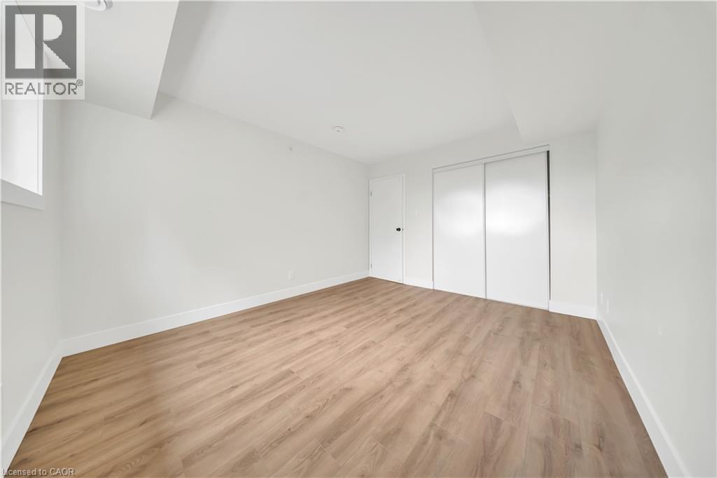 Bright interior room featuring light wood-finish flooring, white walls, and white baseboards - 3085 Kingsway Drive Unit# 21, Kitchener, ON