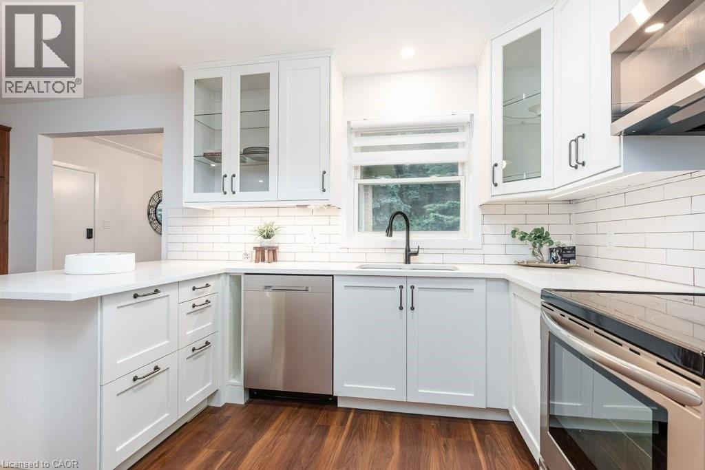 Modern kitchen featuring white shaker-style cabinetry, stainless steel appliances, white subway tile backsplash, and wood-finish flooring - 139 Mackay Crescent, Waterloo, ON