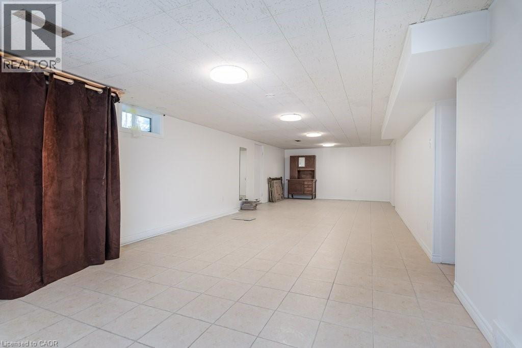 Spacious room featuring light-toned tile flooring, white painted walls, and a white acoustical tile ceiling with multiple flush-mount light fixtures - 139 Mackay Crescent, Waterloo, ON