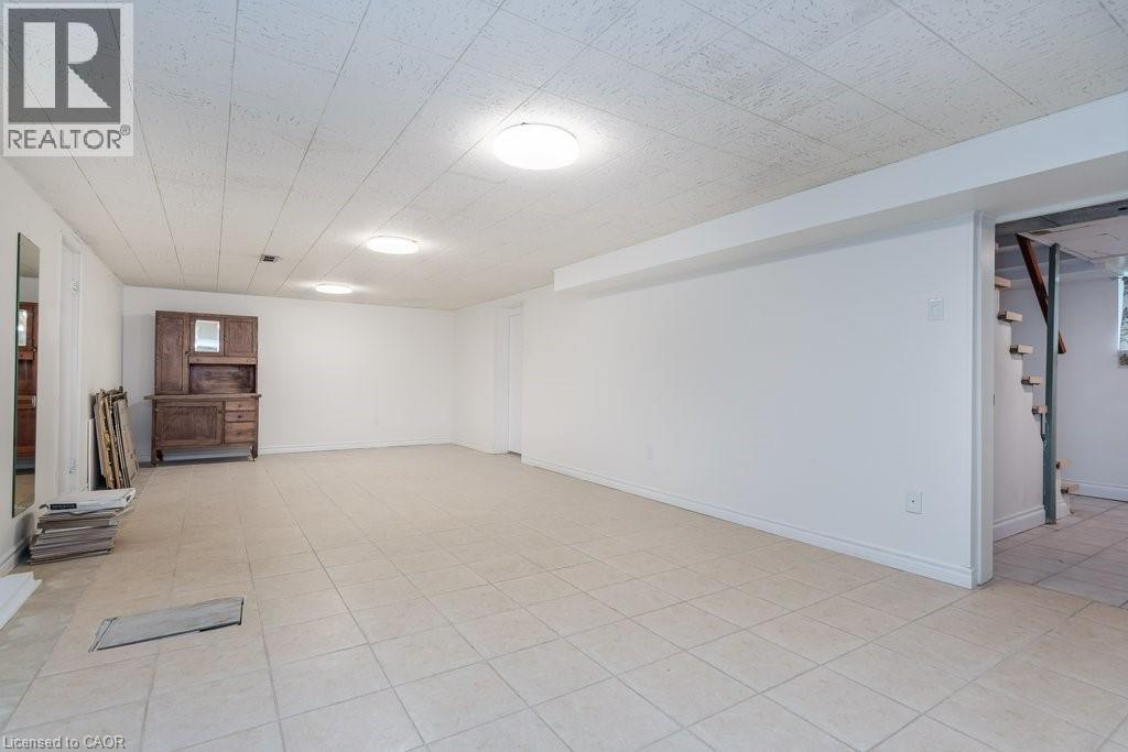Spacious open-concept room featuring light-toned tile flooring, recessed overhead lighting, and crisp white walls - 139 Mackay Crescent, Waterloo, ON