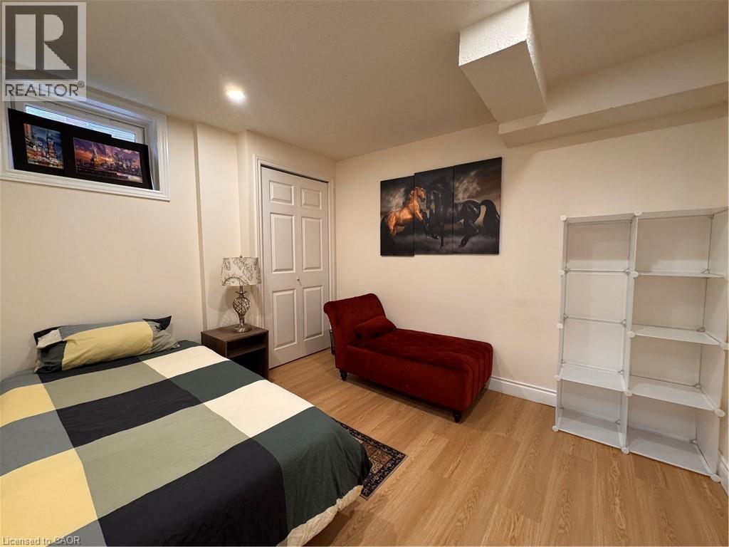 Neutral-toned walls and wood-finish flooring define this room, featuring a double-pane window, white baseboards, and a two-panel door - 110 Marl Meadow Drive Unit# B, Kitchener, ON