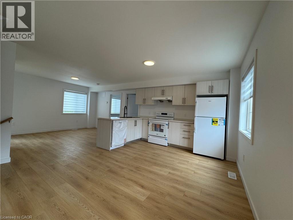 Open-concept kitchen and living area featuring wood-finish flooring, recessed lighting, and ample natural light from multiple windows - 113 Highriver Trail Unit# Main, Welland, ON - Indoor Photo Showing Kitchen
