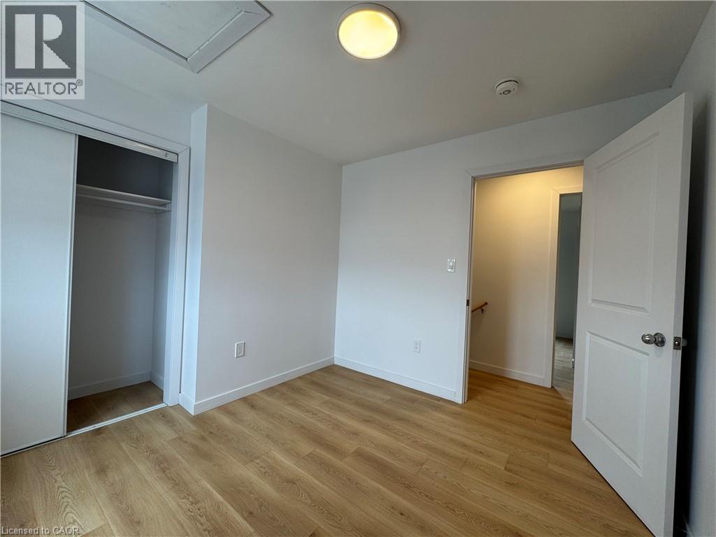 Room featuring wood-finish flooring, white walls, and a built-in closet with sliding doors - 113 Highriver Trail Unit# Main, Welland, ON - Indoor Photo Showing Other Room