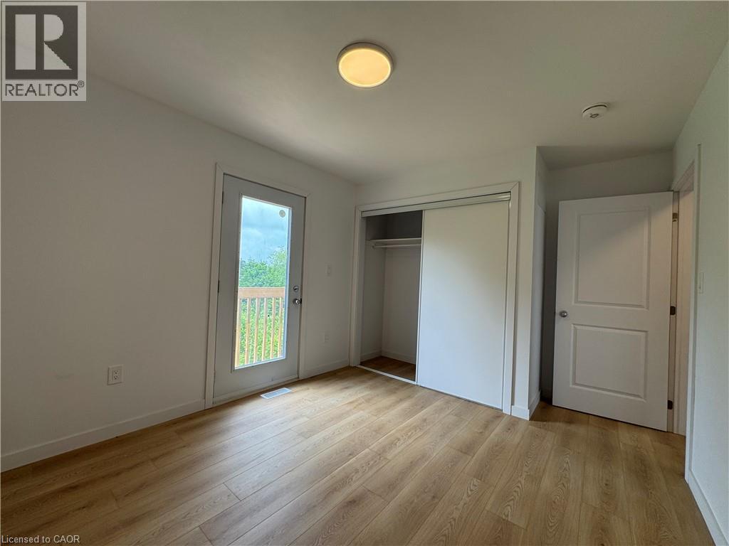 Interior room featuring wood-finish flooring, white walls, and a flush mount ceiling light - 113 Highriver Trail Unit# Main, Welland, ON - Indoor Photo Showing Other Room
