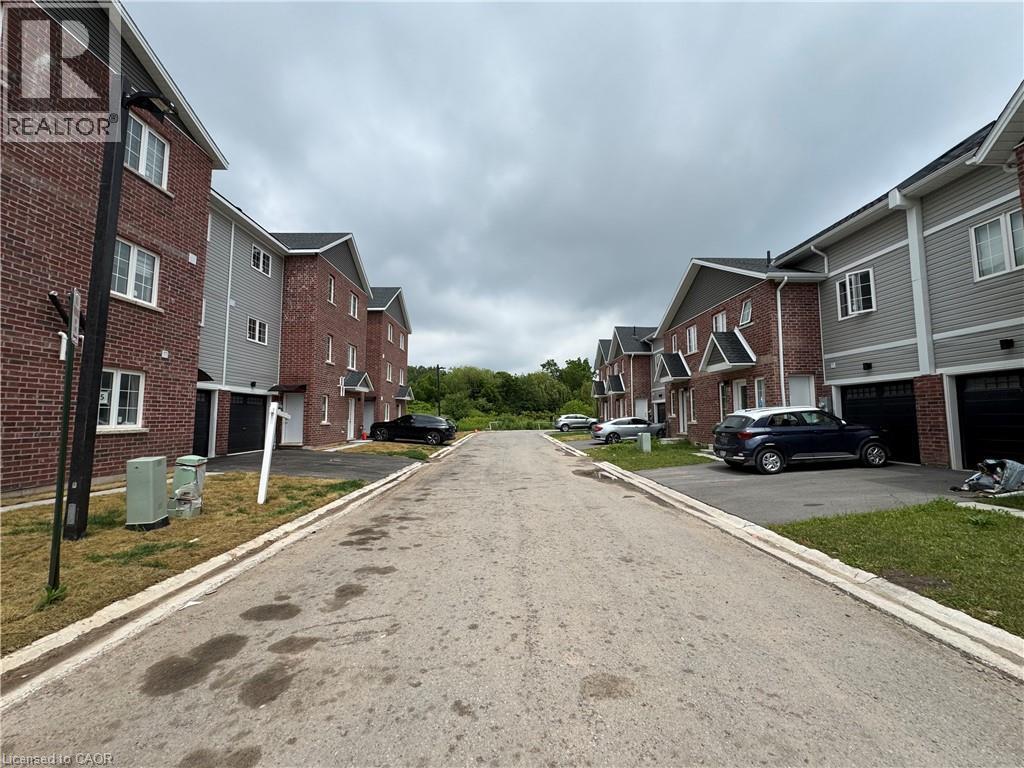 Contemporary townhomes featuring brick and siding exteriors, individual garages with black doors, and white-trimmed windows - 113 Highriver Trail Unit# Main, Welland, ON - Outdoor