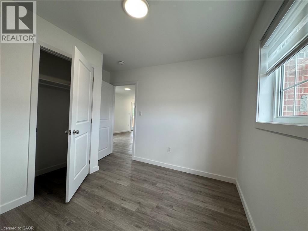 Bedroom featuring wood-finish flooring, white walls, and a window with blinds - 119 Highriver Trail Unit# Main, Welland, ON - Indoor Photo Showing Other Room