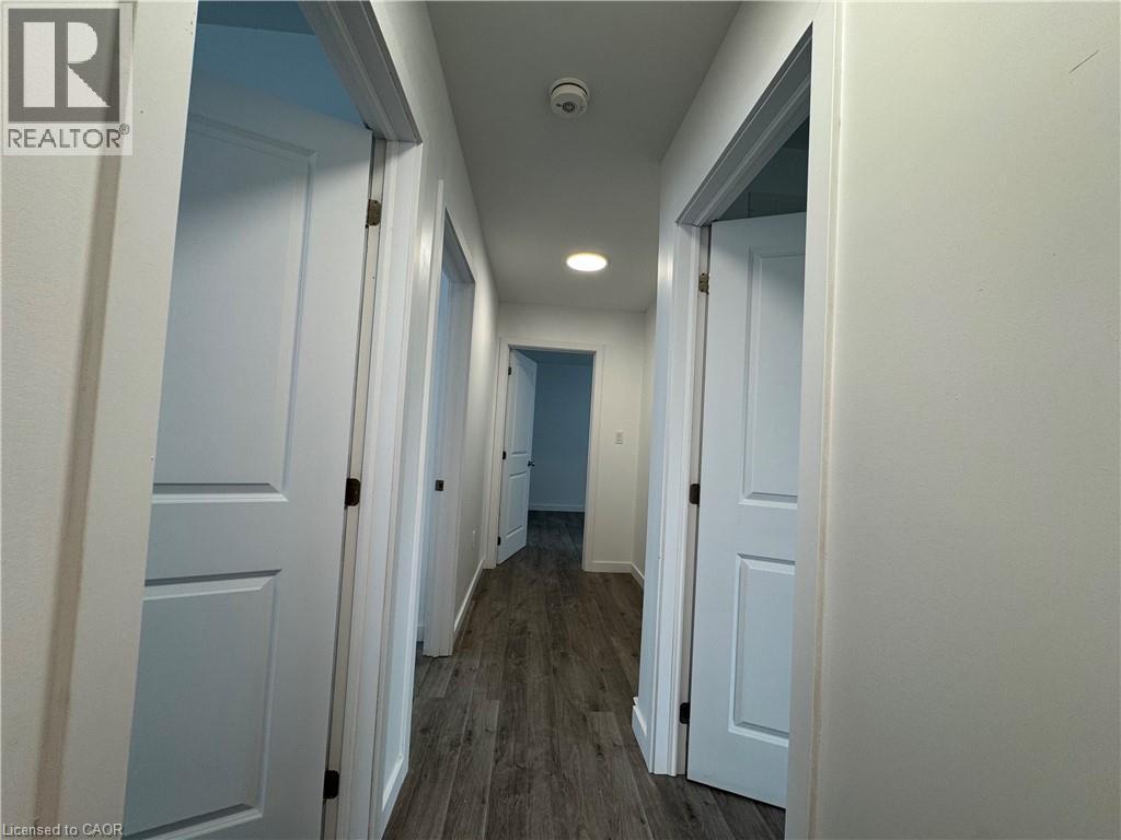 Hallway featuring wood-finish flooring, recessed lighting, and multiple white paneled doors - 119 Highriver Trail Unit# Main, Welland, ON - Indoor Photo Showing Other Room